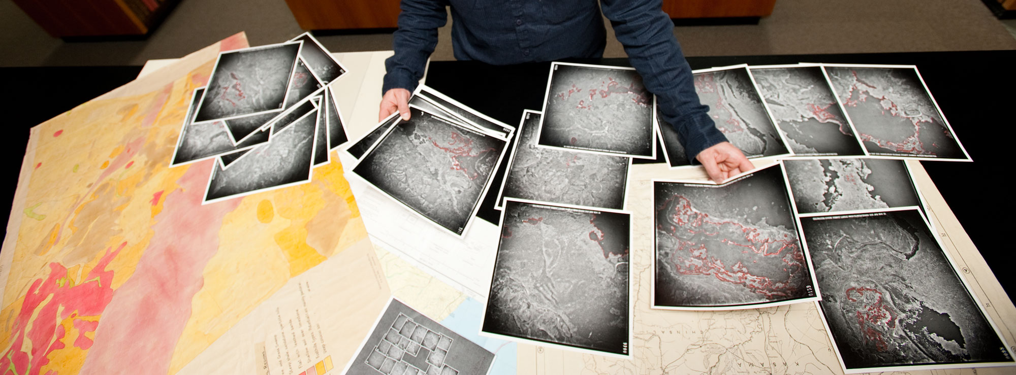 Researcher with table full of map print outs