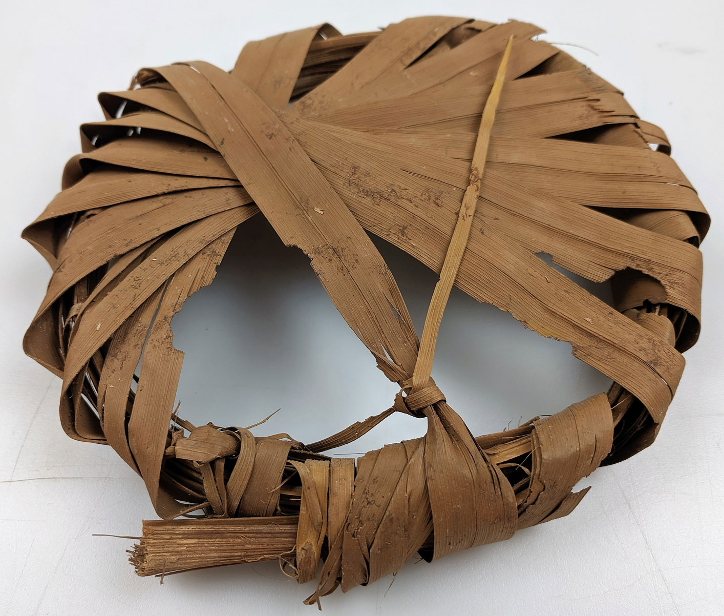A round brown Egyptian object made out of date palm leaves.