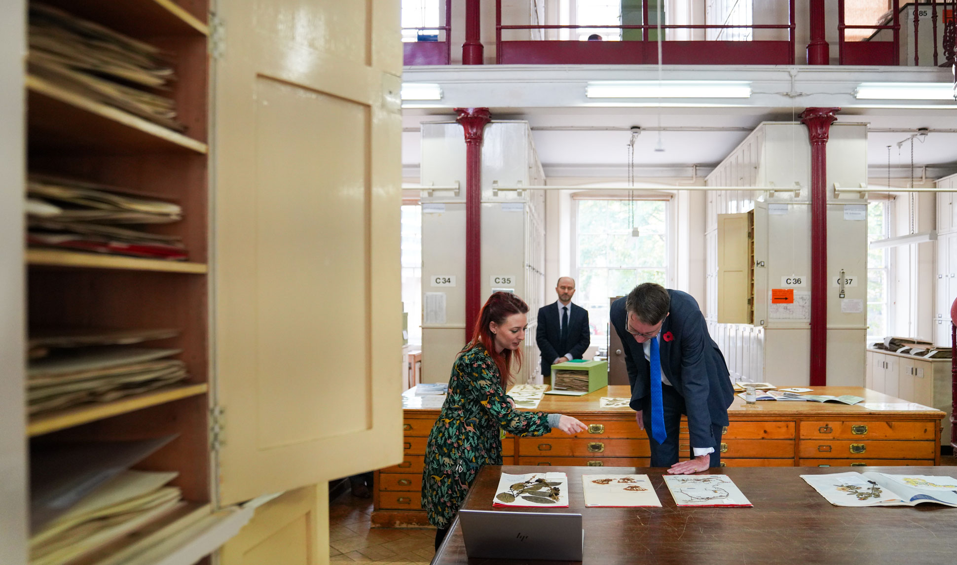 Kew scientist pointing at specimen on a table in Kew's Herbarium with Chief Secretary to the Treasury Simon Clarke 