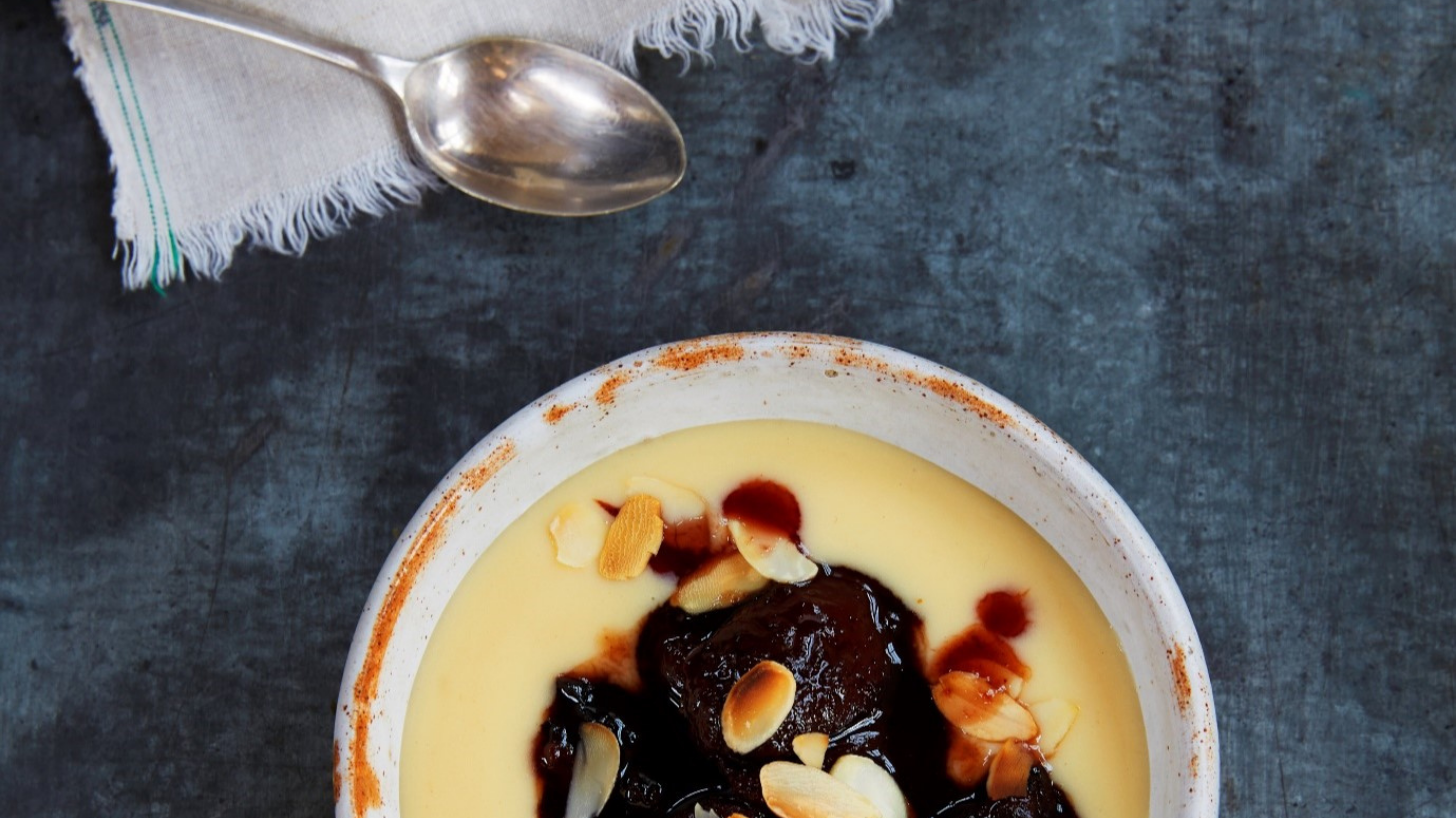 Dried fruit compote with custard in a white bowl