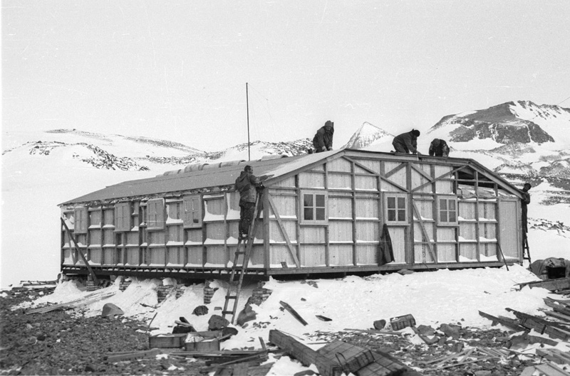 A black an white image of people working on a building in a polar environment