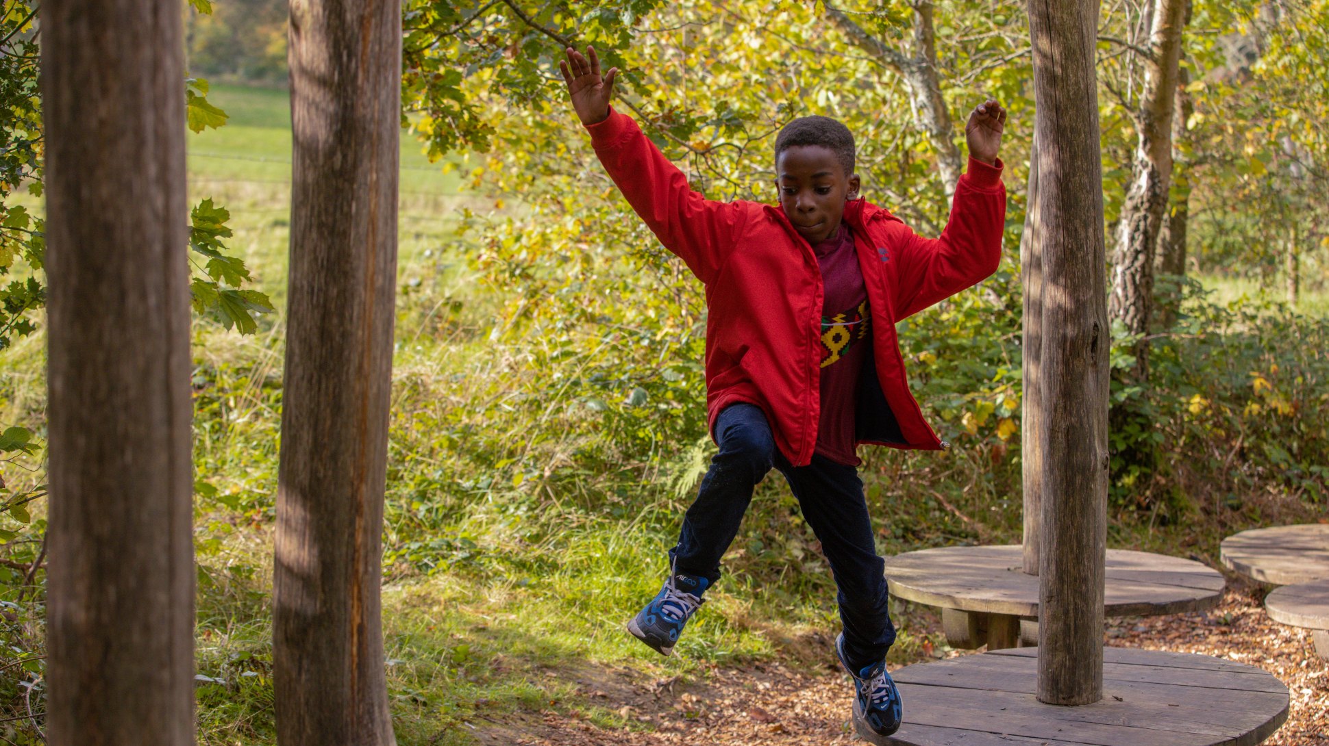 A child in a red coat jumps in a forest