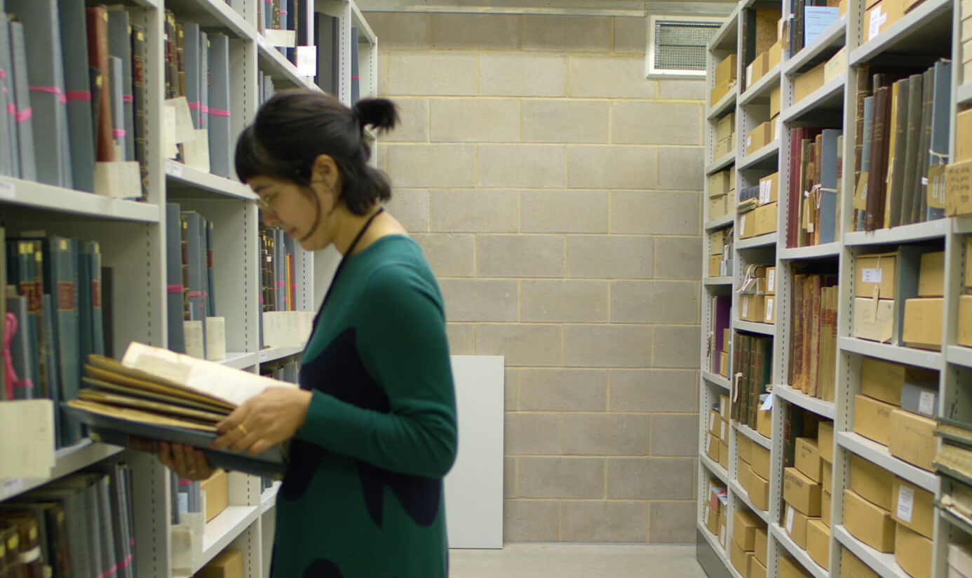 Artist Anushka Tay researching the Miscellaneous Reports volumes inside the Archive store at the Royal Botanical Gardens, Kew