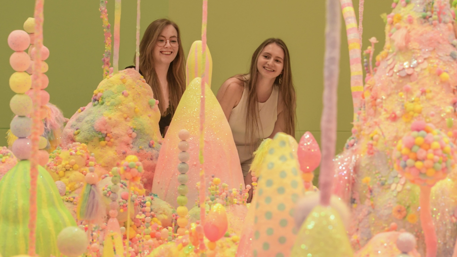 Two visitors explore the colourful When Flowers Dream exhibition 