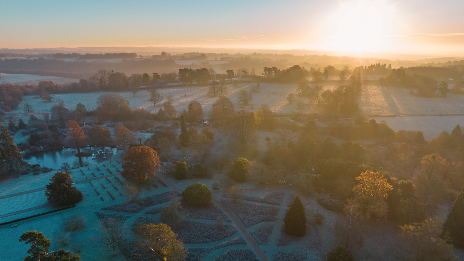 A drone shot of a sunrise over the Wakehurst landscape