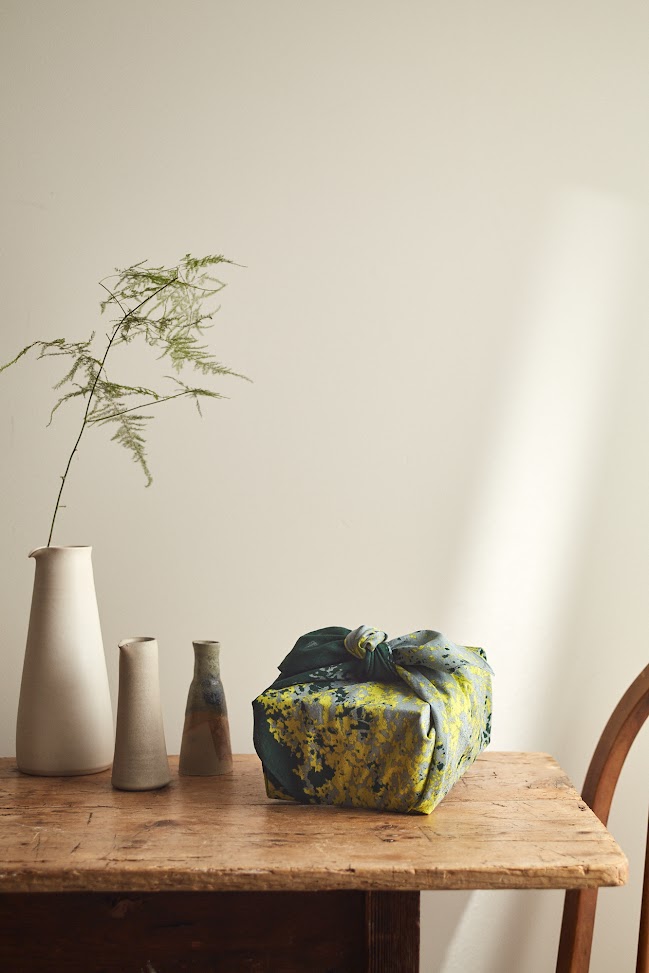 A beautifully wrapped gift on a wooden table with clay vases
