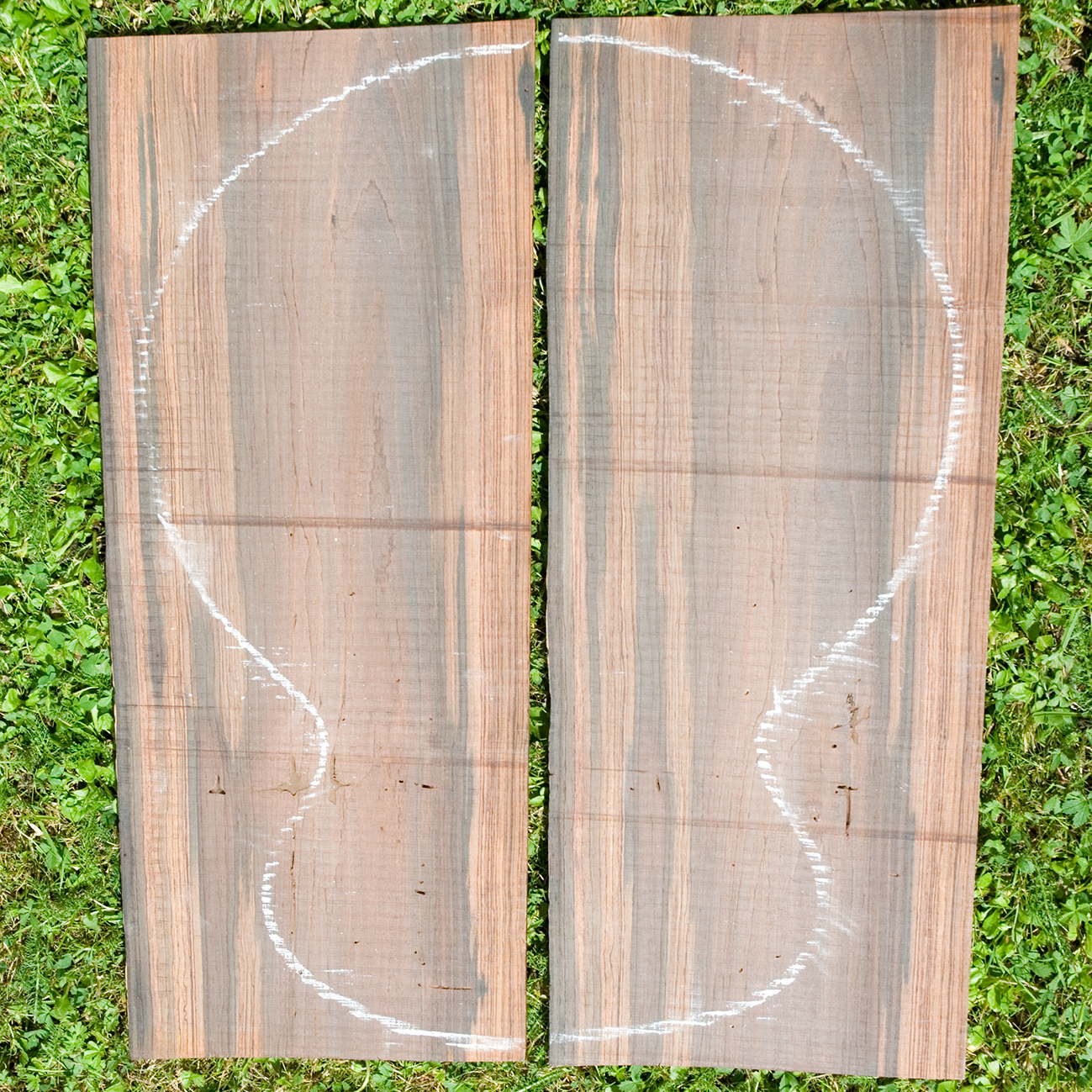 Two planks of wood with the outline of a guitar marked on with chalk.