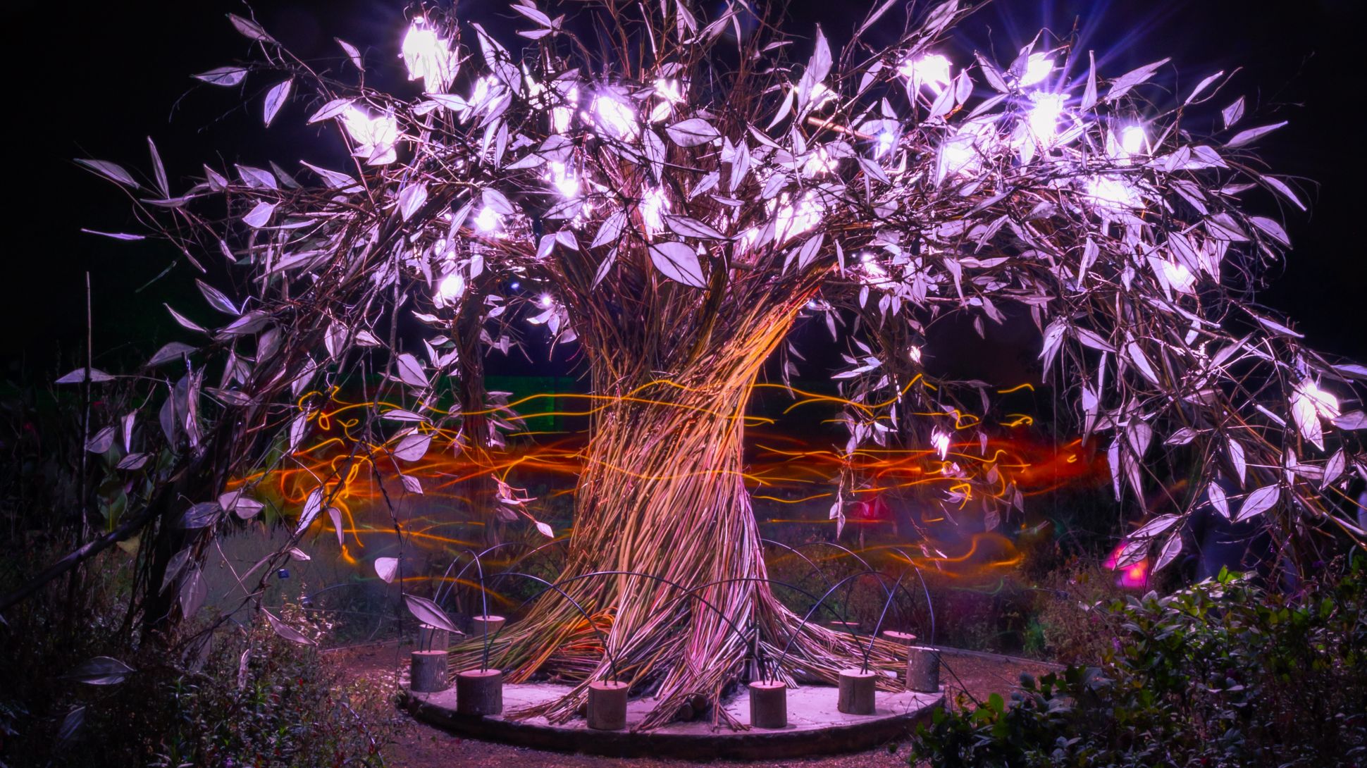 A sculpture of a tree with illuminated purple leaves