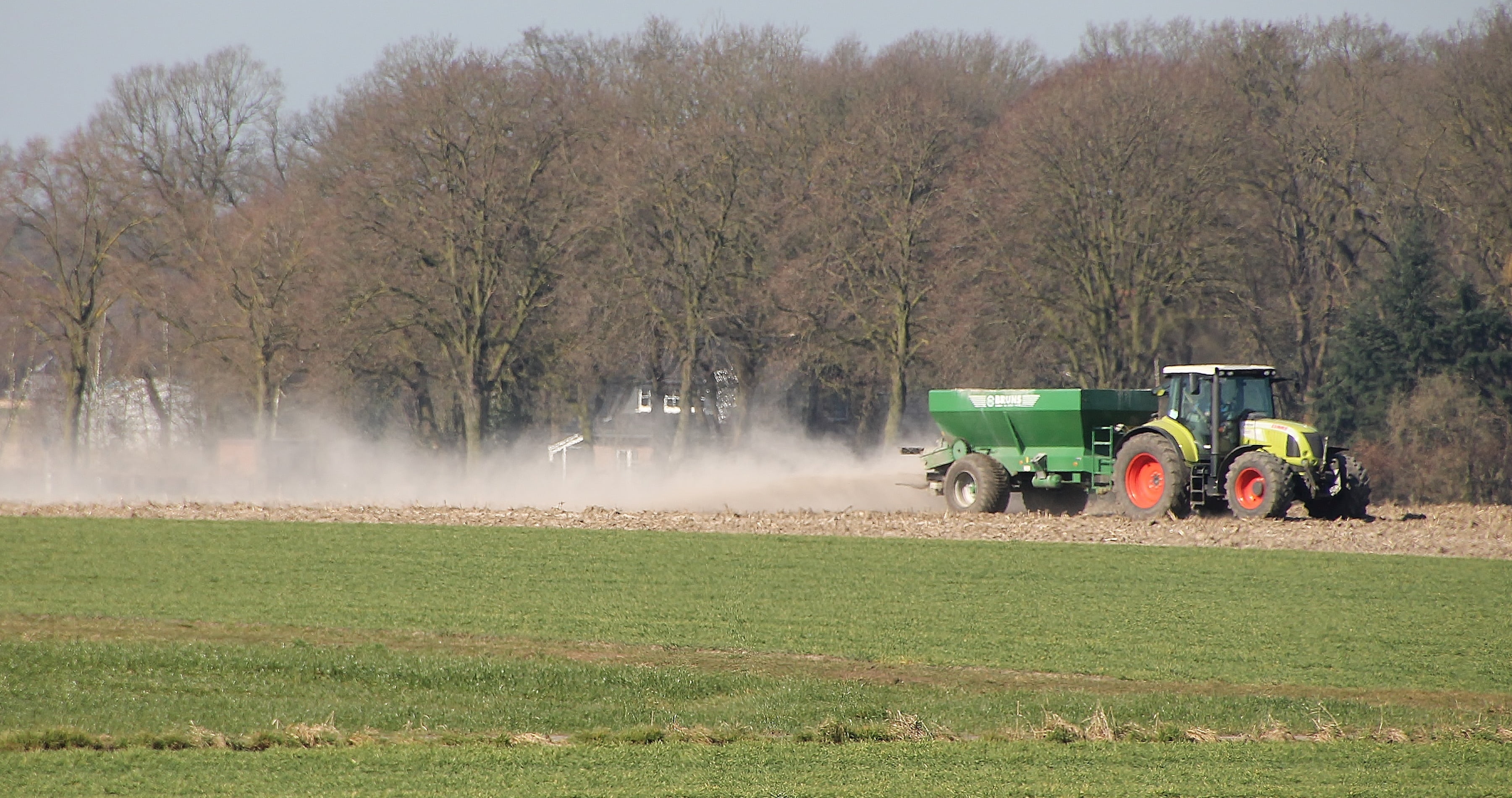 A tractor sprays fertiliser over a field