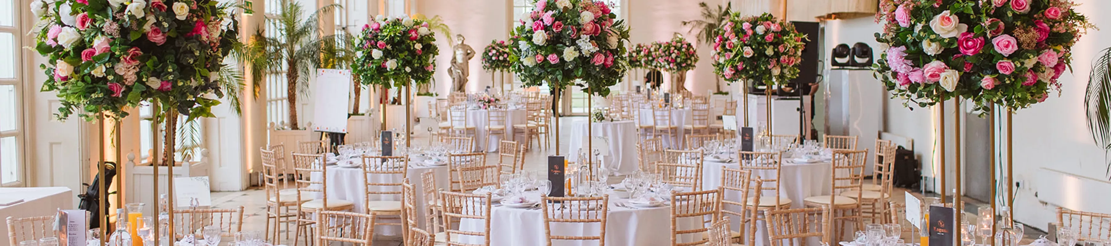 Round tables, large flower arrangements and wooden chairs at a wedding at Kew