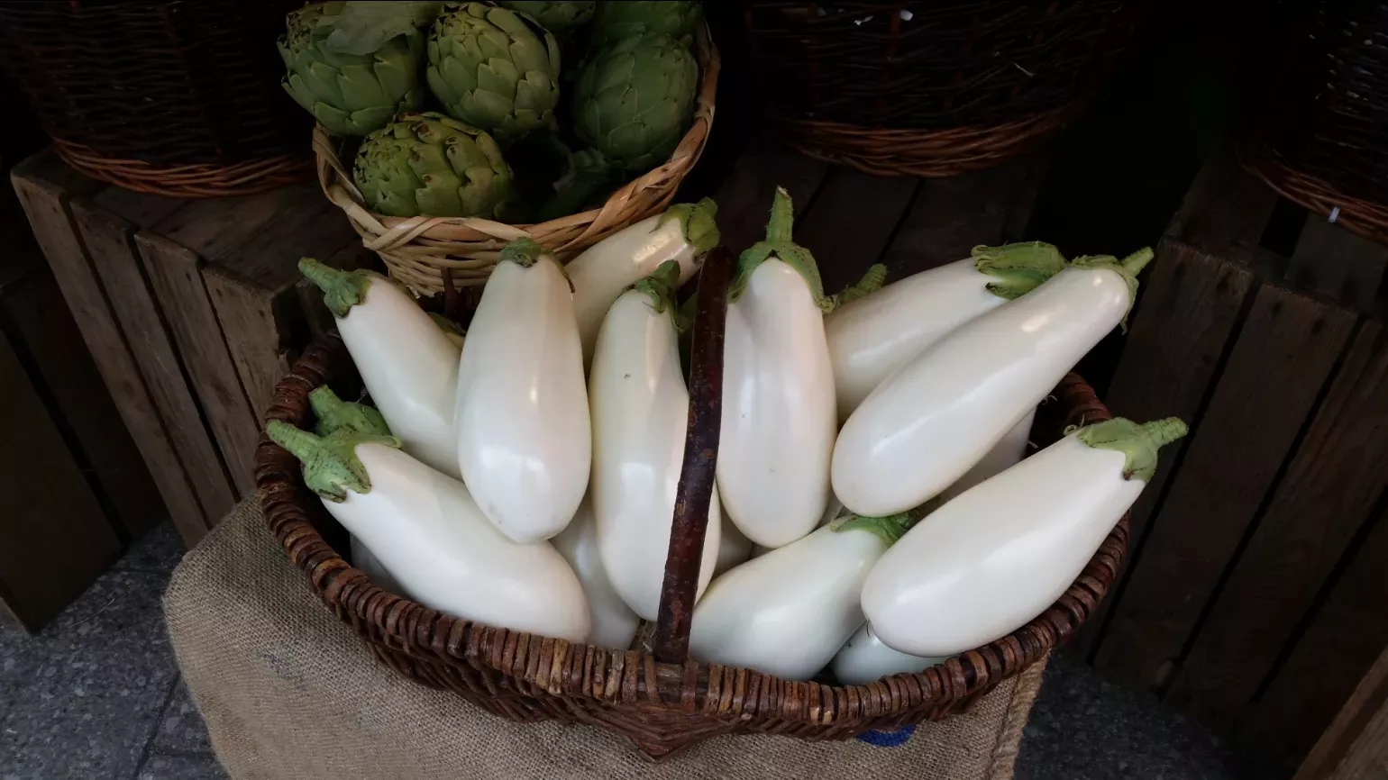 Several white aubergine fruit in a basket