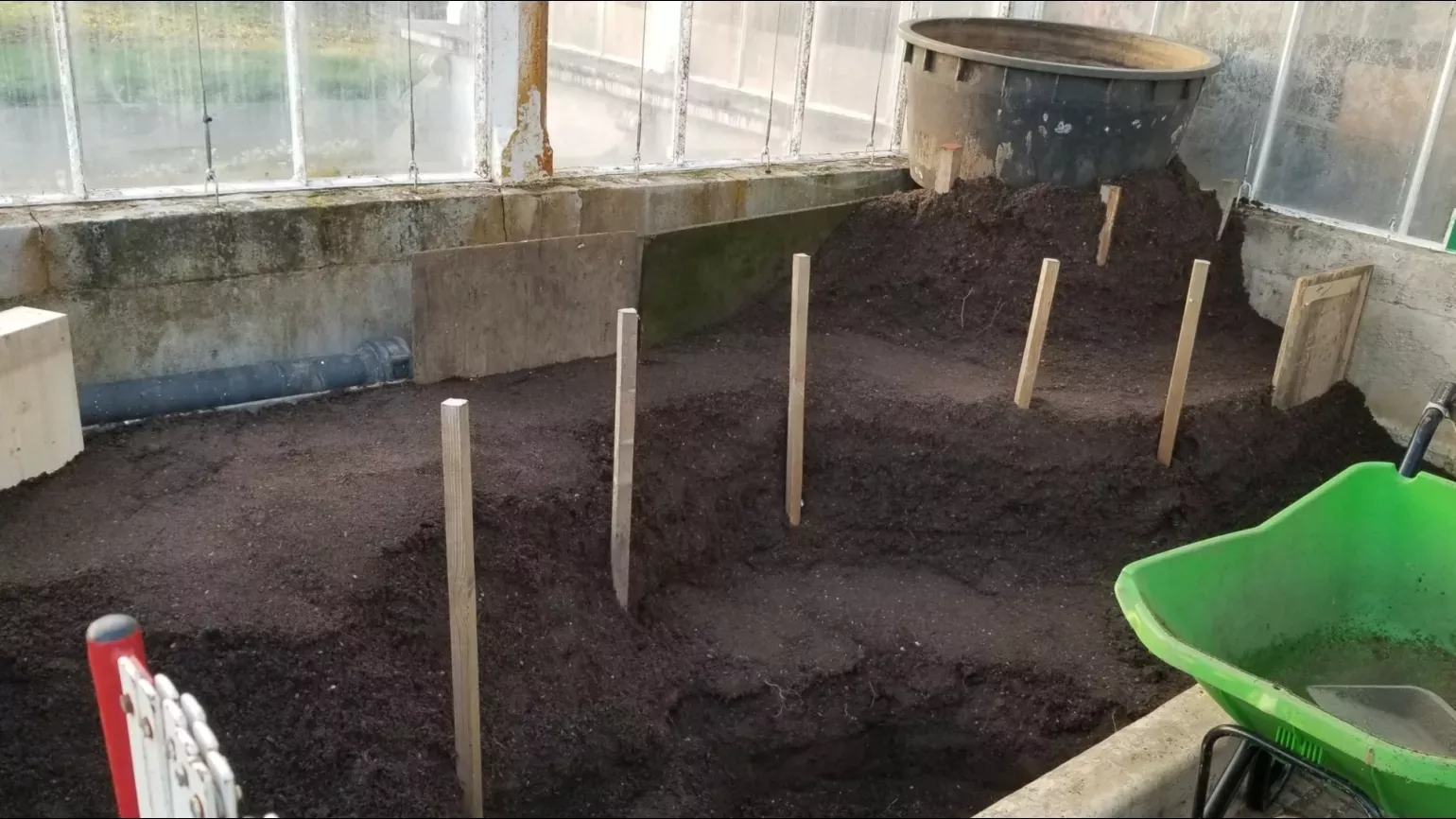 A planter filled with earth and wooden stakes