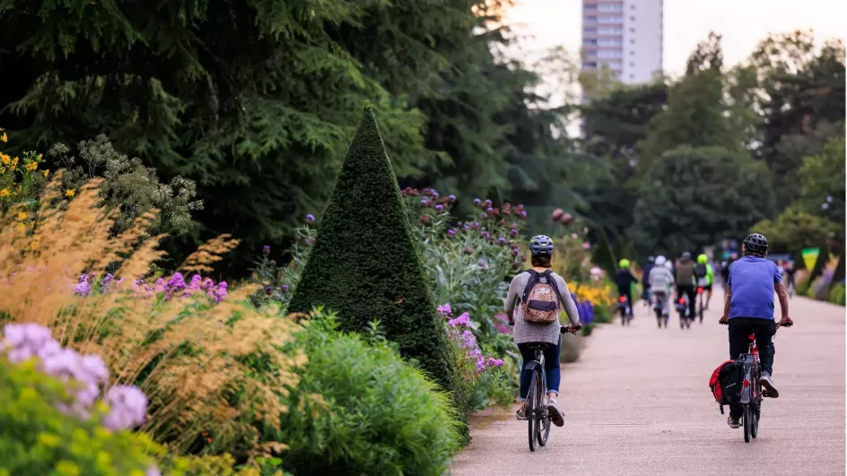 People on bikes next to large floral borders