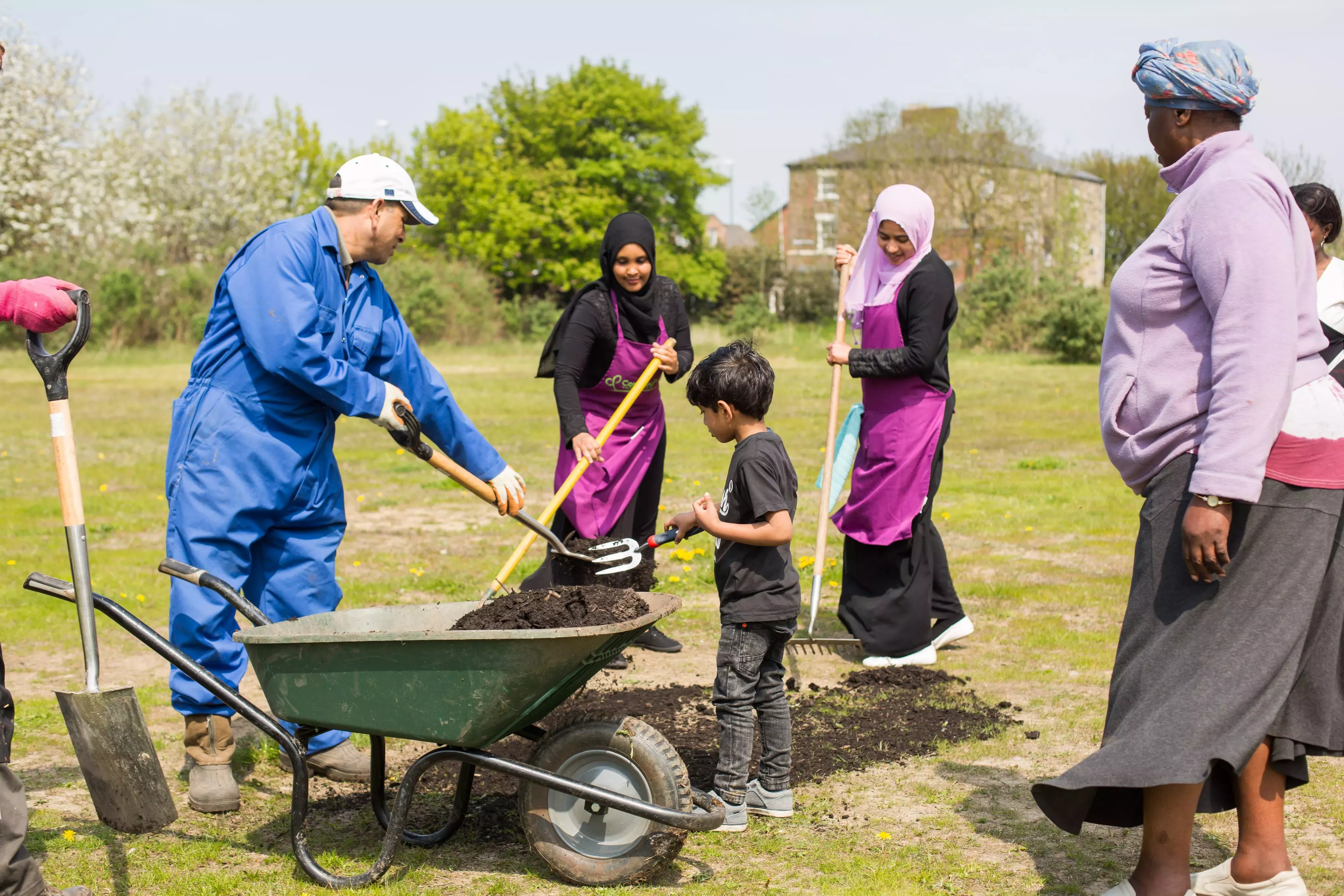 Women and children take part in an outreach project,putting soil into a wheelbarrow