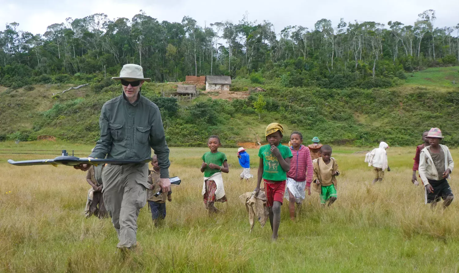 Tim carrying a drone with a group of Madagascan children following.