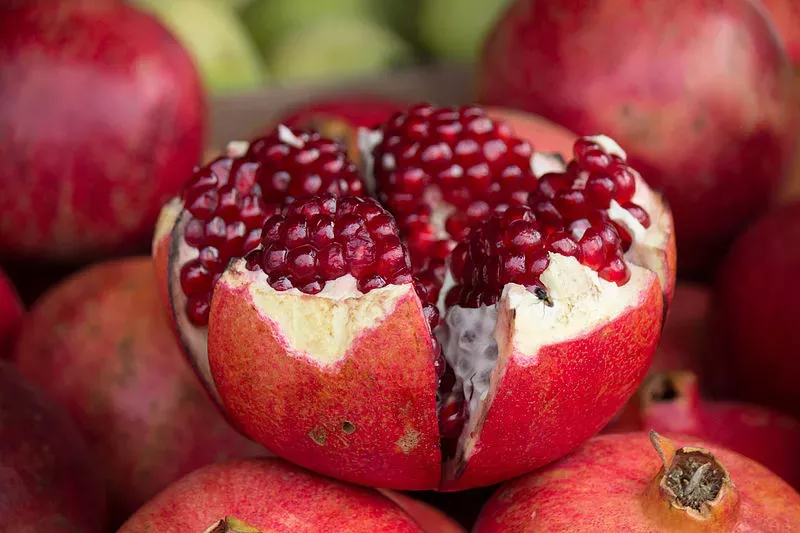 Open pomegranate (Punica granatum) fruit that is spherical and red with deep red tissue surrounding seeds