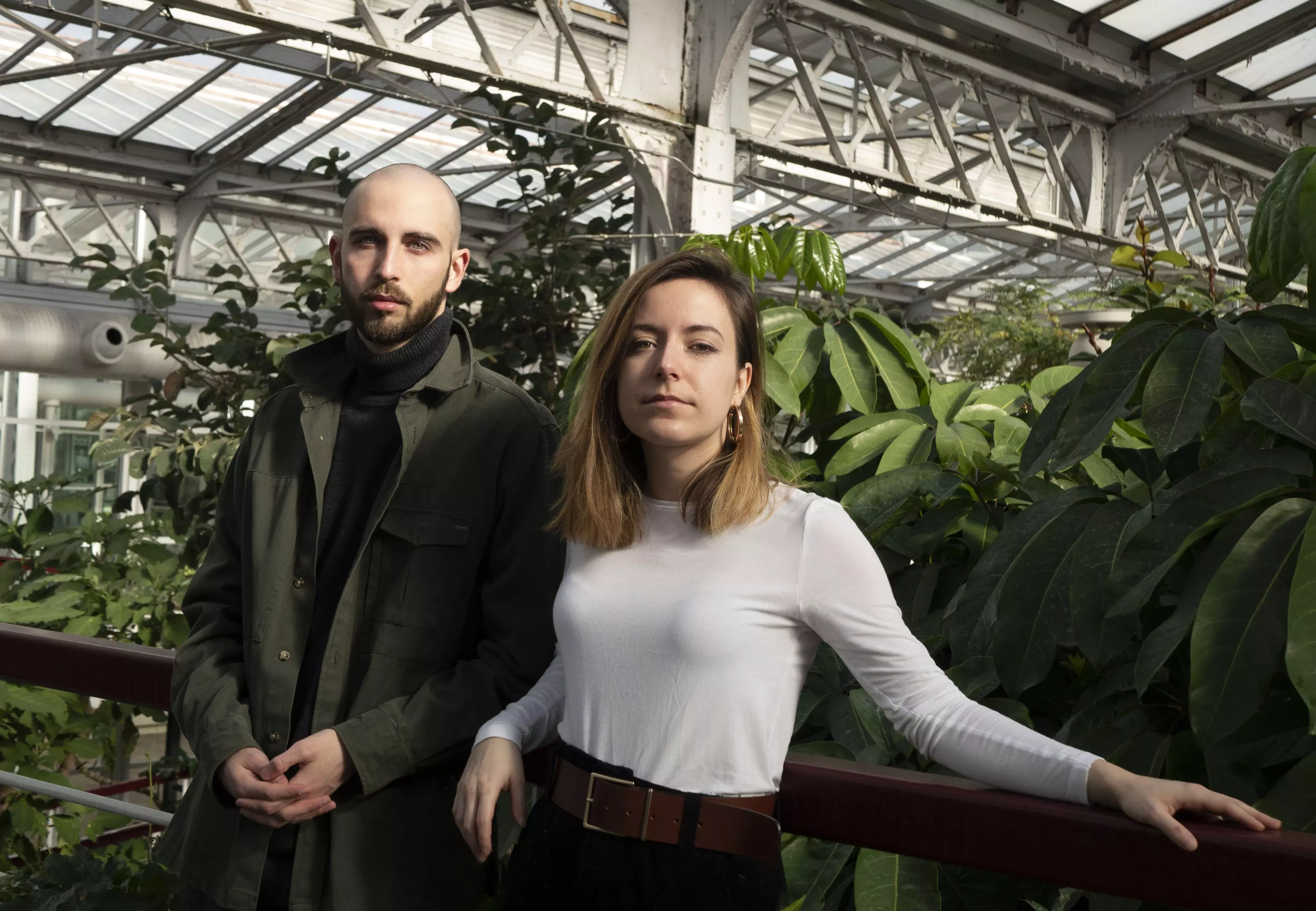Man and woman standing in front of a glasshouse filled with greenery