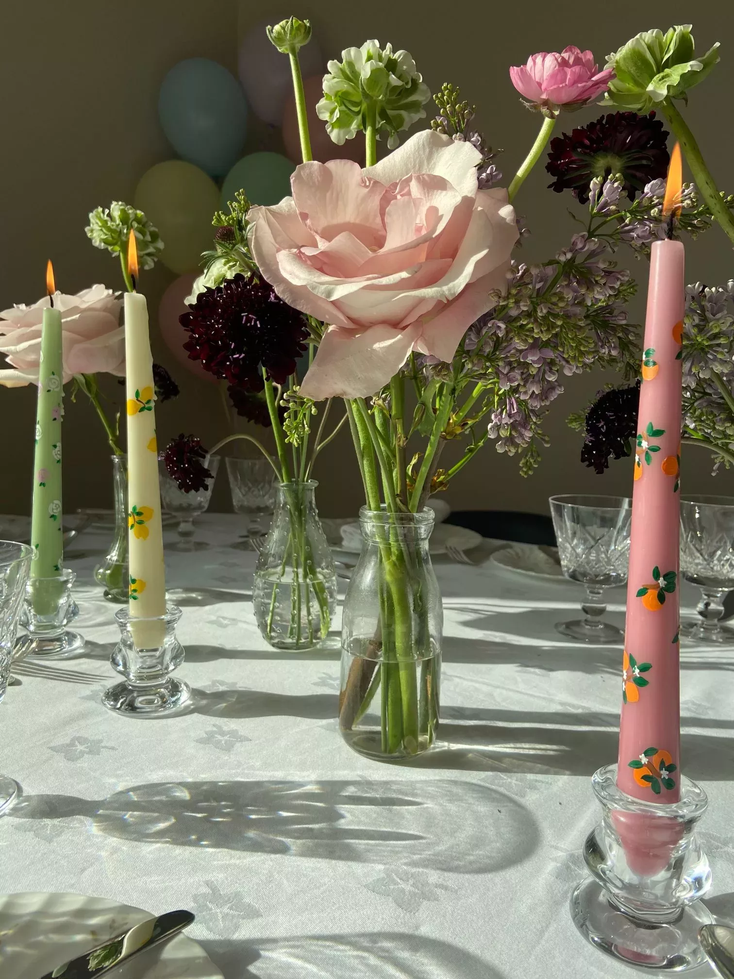 Painted botanical candles on a table with flowers