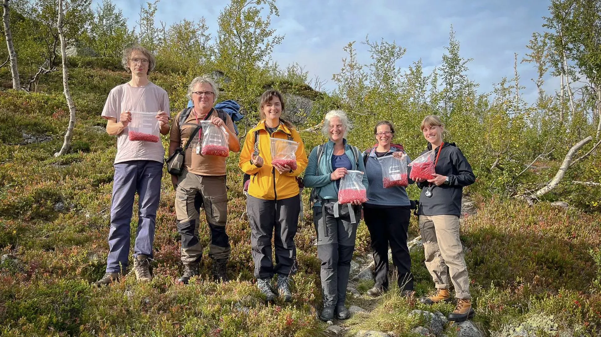A group of people holding bags full of seeds in the arctic countryside